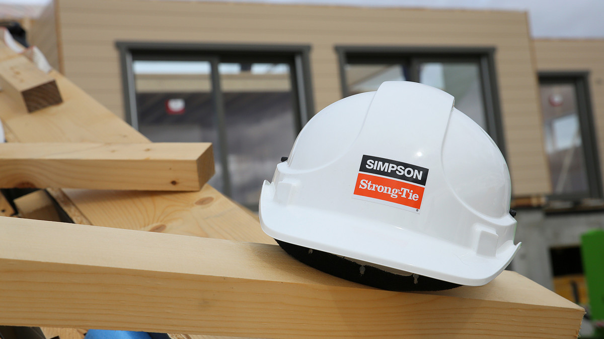Lautojen päällä valkoinen rakennuskypärä, jossa Simpson Strong-Tie-logo