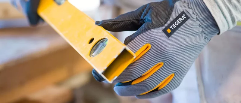 Kuvassa TEGERA-hansikkaalla suojattu käsi pitelee vatupassia.